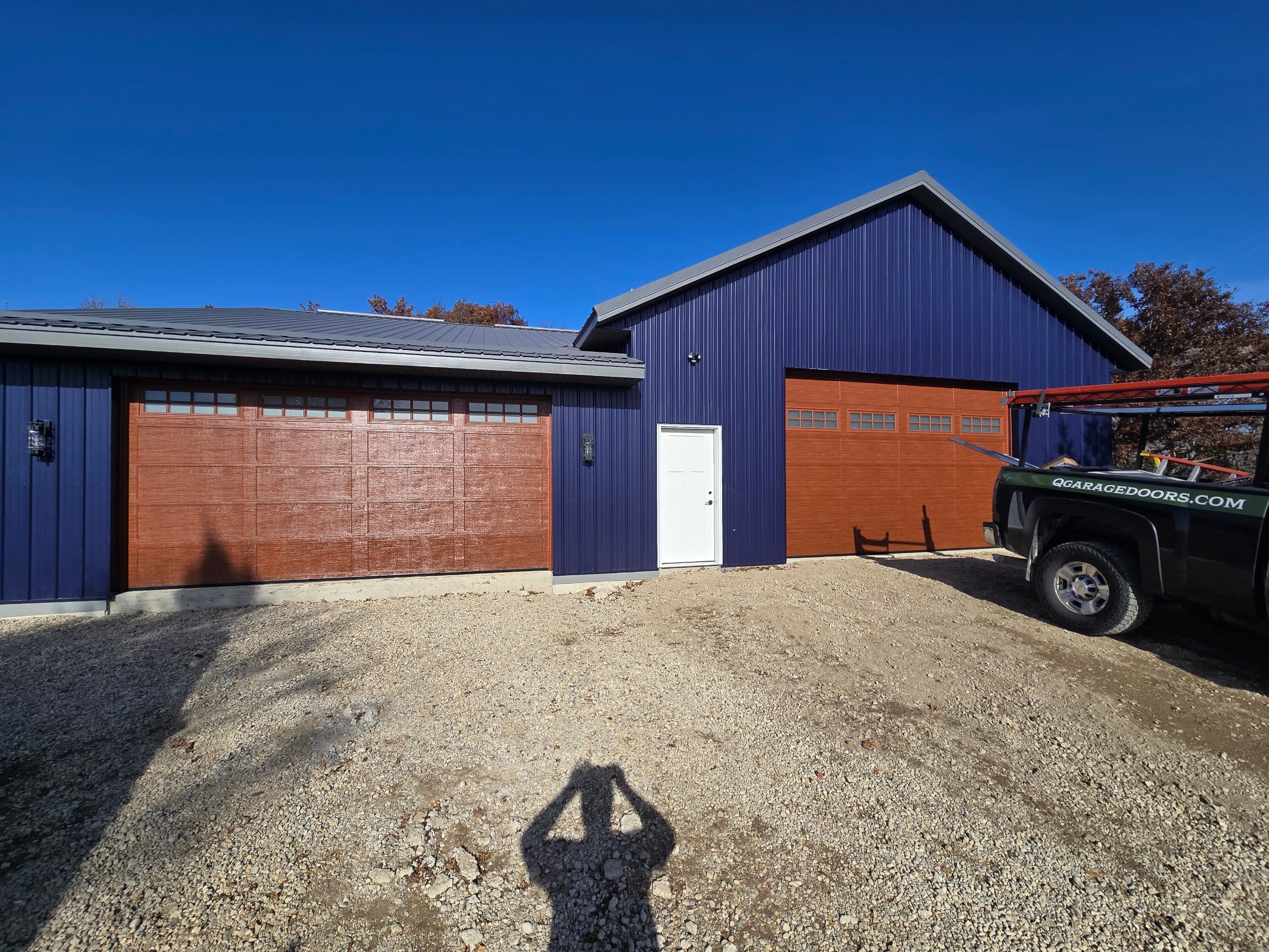 Two cedar-tone garage doors on a steel-blue pole building