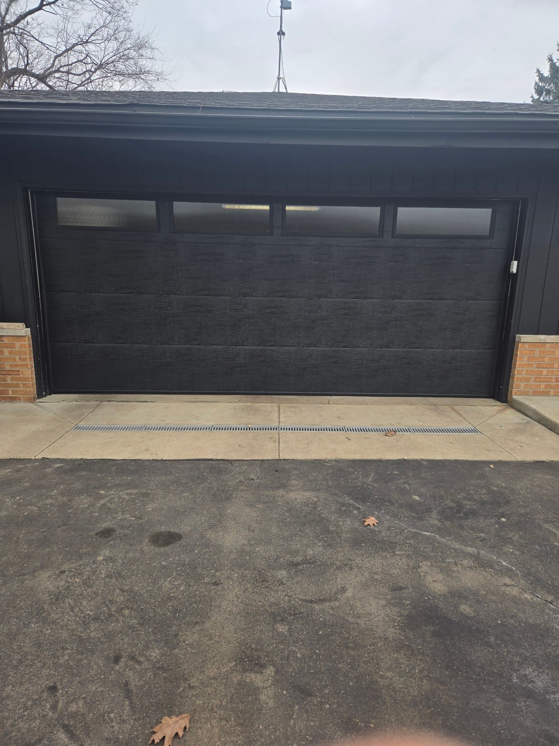 Black flush-panel garage door with frosted glass top row